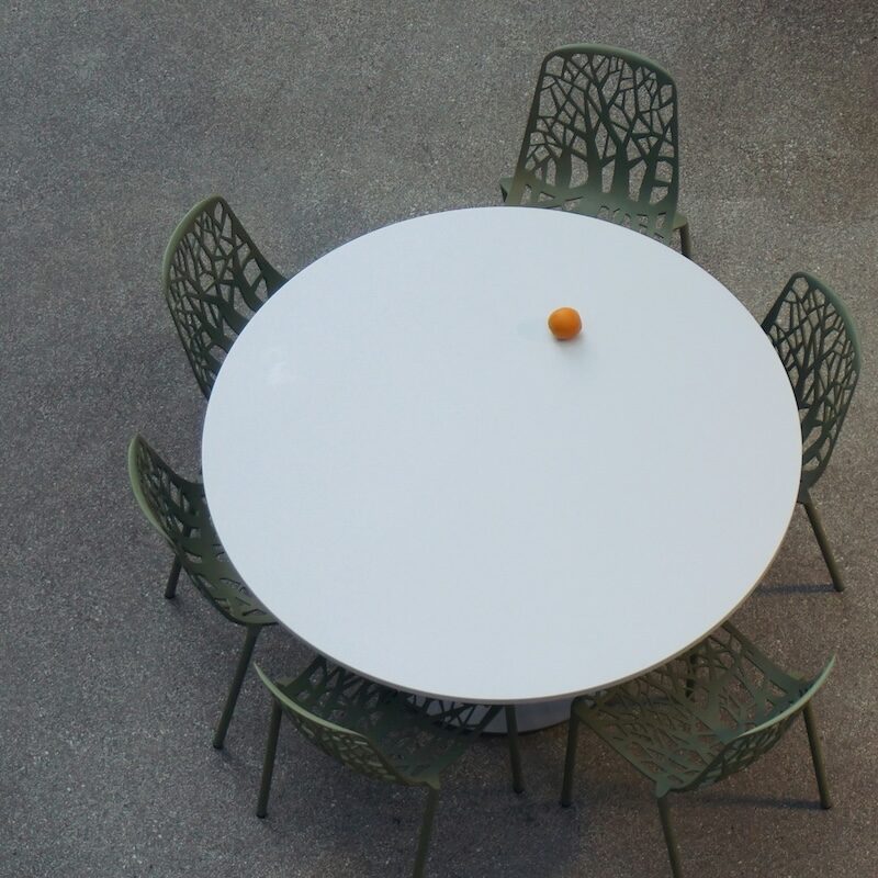 a round table with chairs and an orange on the table